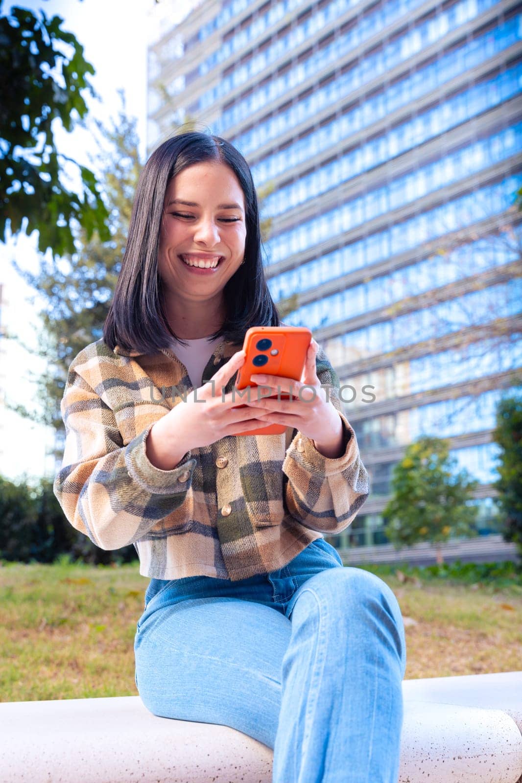 Young smiling student uses social networks with smartphone applications and wireless technology outdoors.Vertical