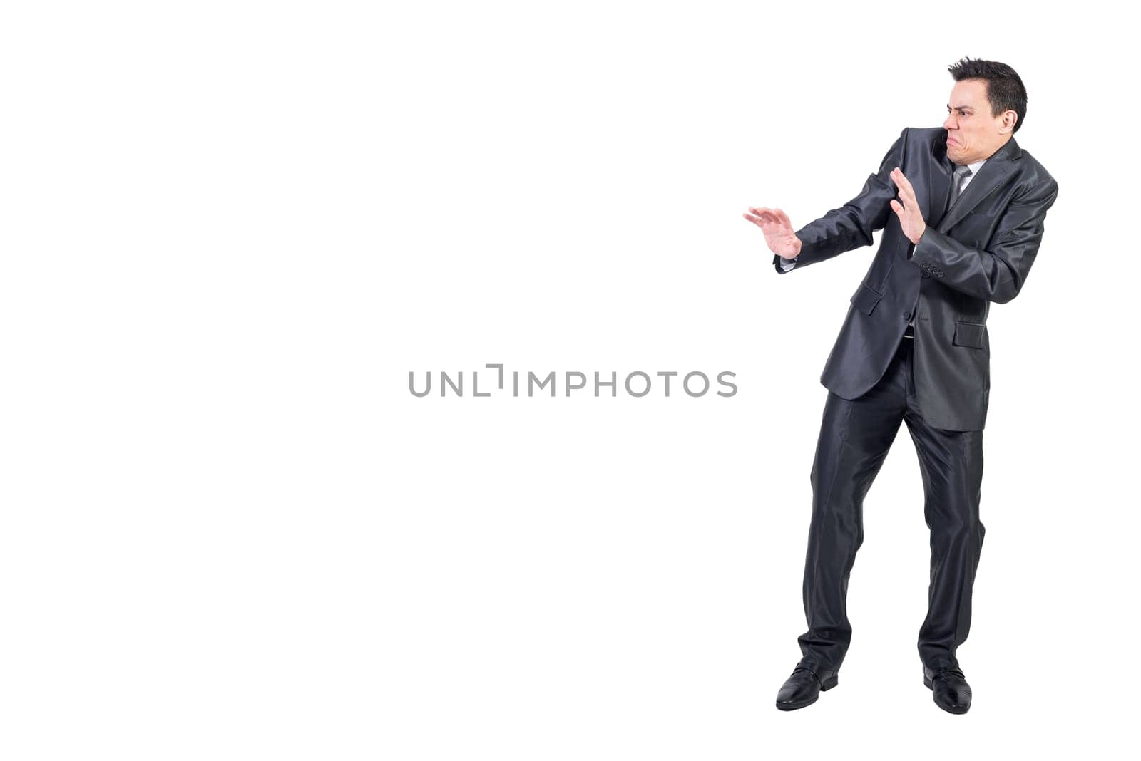Full body of unpleasant male with disgusted face in elegant suit standing isolated on white background in modern light studio