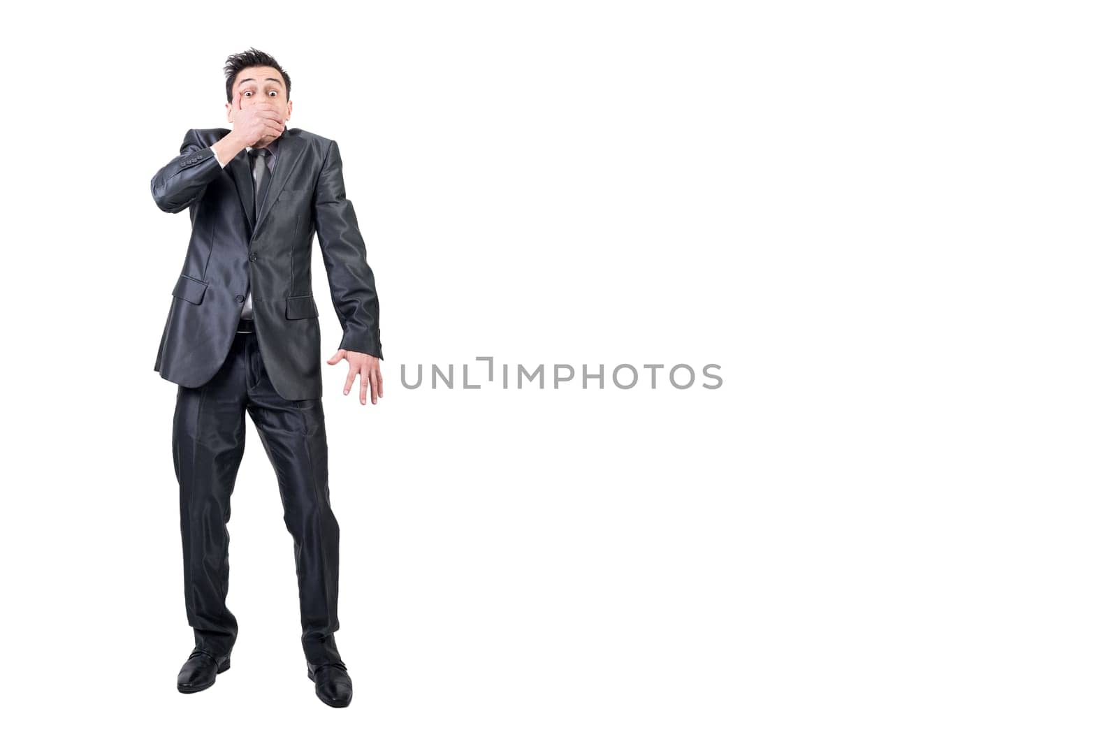 Full body of male loudmouth in formal suit looking at camera while covering mouth isolated on white background in studio
