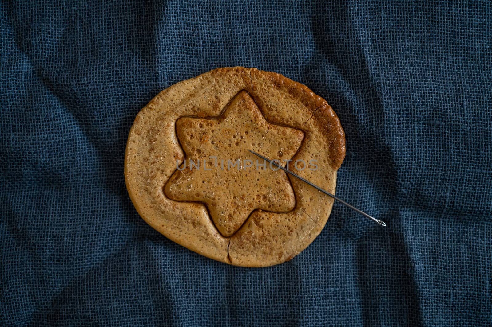 Brown sugar caramel candy cookies with a metal needle in the shape of a star. Concept of survival game