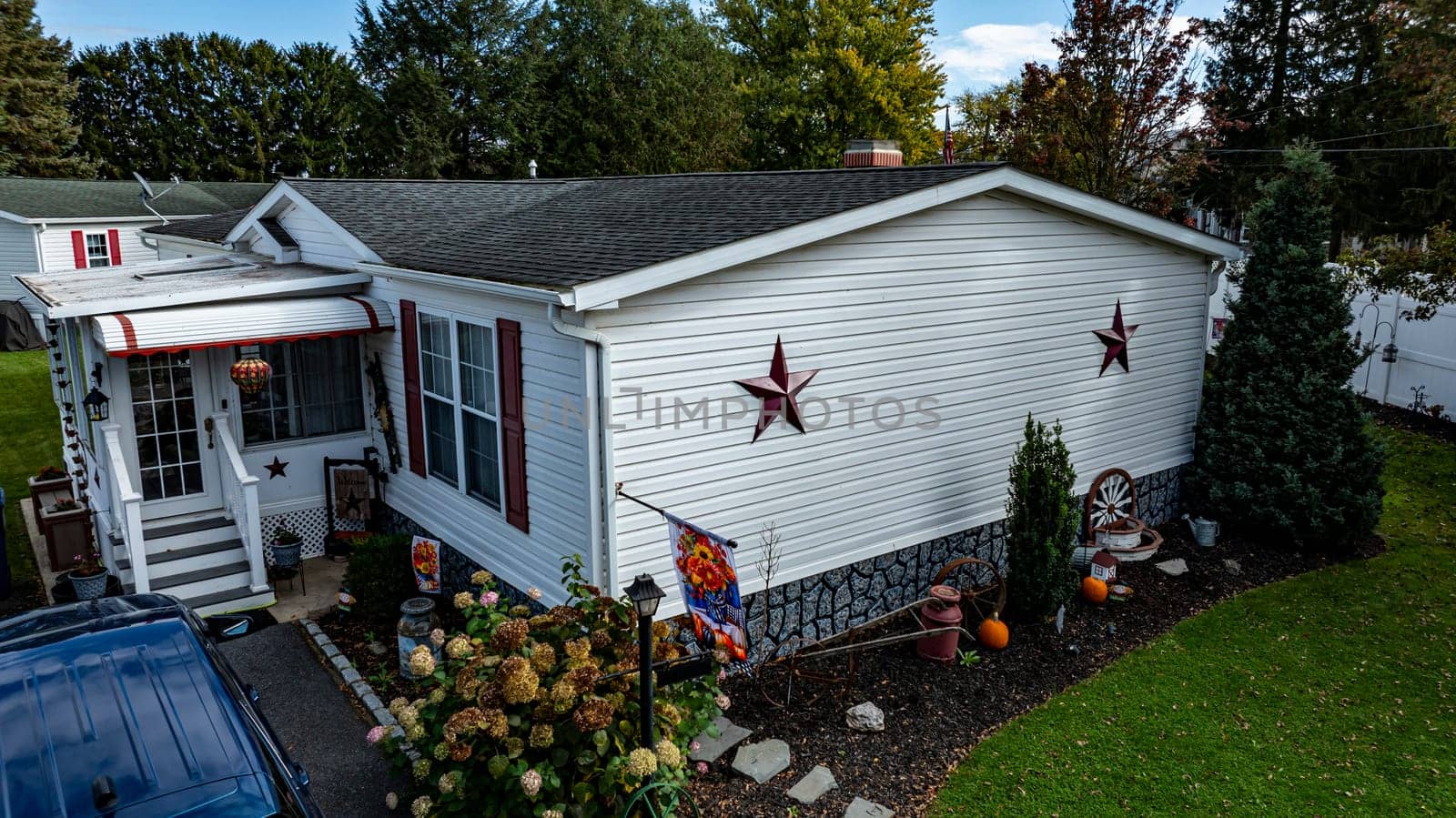 A well-maintained Mobile, Prefab, Manufactured, house features star decorations and a colorful garden, showcasing a cozy atmosphere in a residential area.