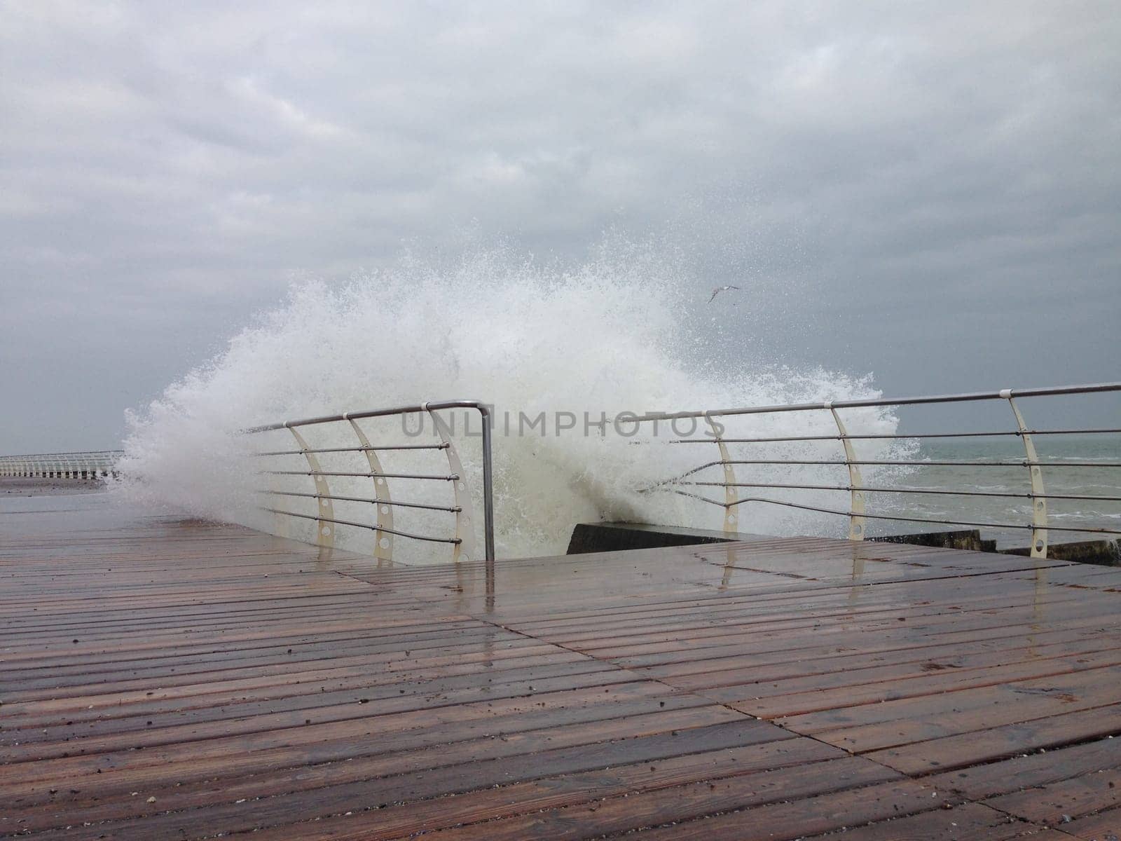 Stormy waves splashing on the wooden decked promenade by Maksym