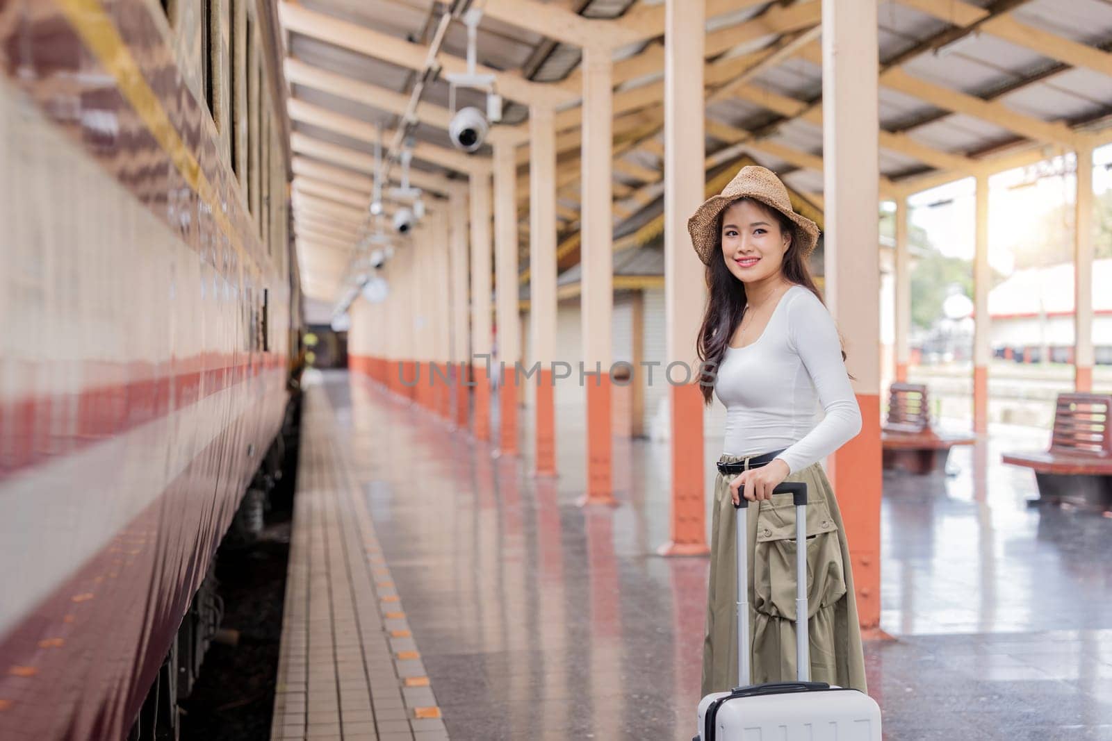 Asian women waiting for train station and carrying a suitcase planning happy holiday vacation.