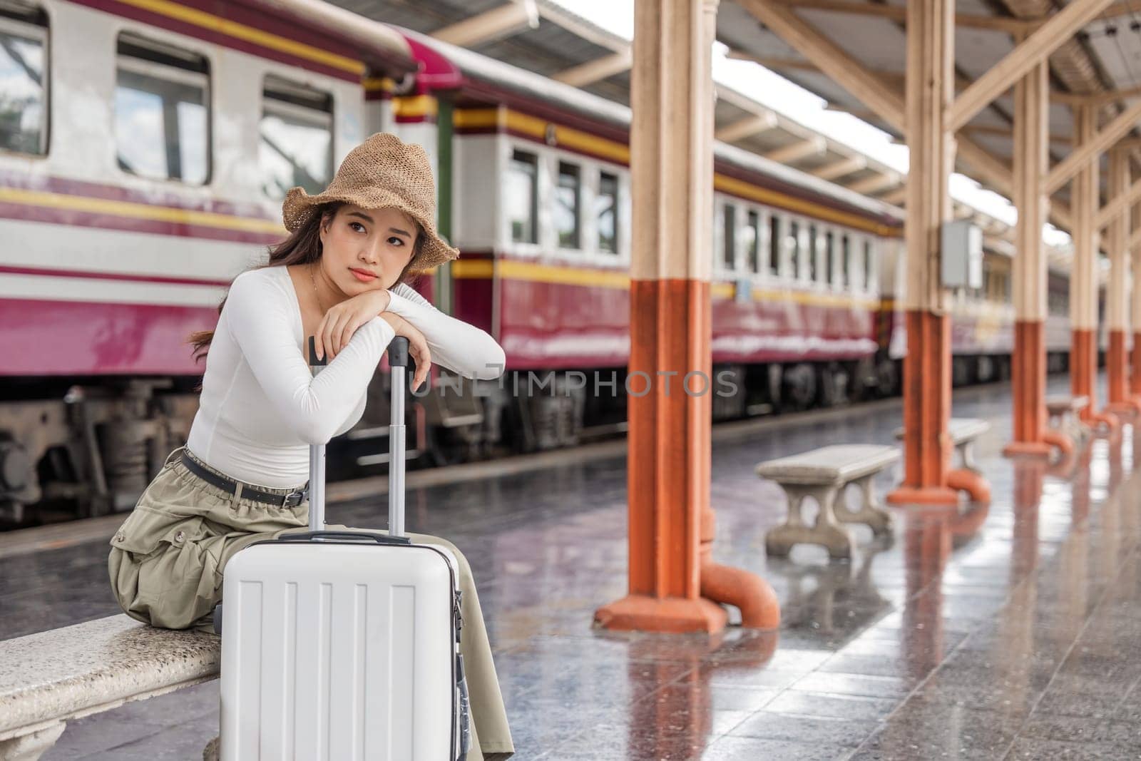 Young woman asian sitting and waiting for the train waiting for the train to go traveling. Travel concept.