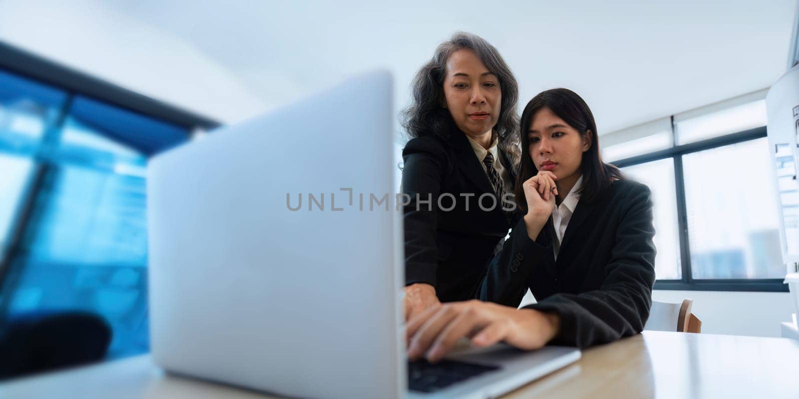 Mentor, coaching or business woman with laptop, speaking or planning a project in office. Technology, teamwork collaboration senior manager explaining to an intern for digital training by nateemee