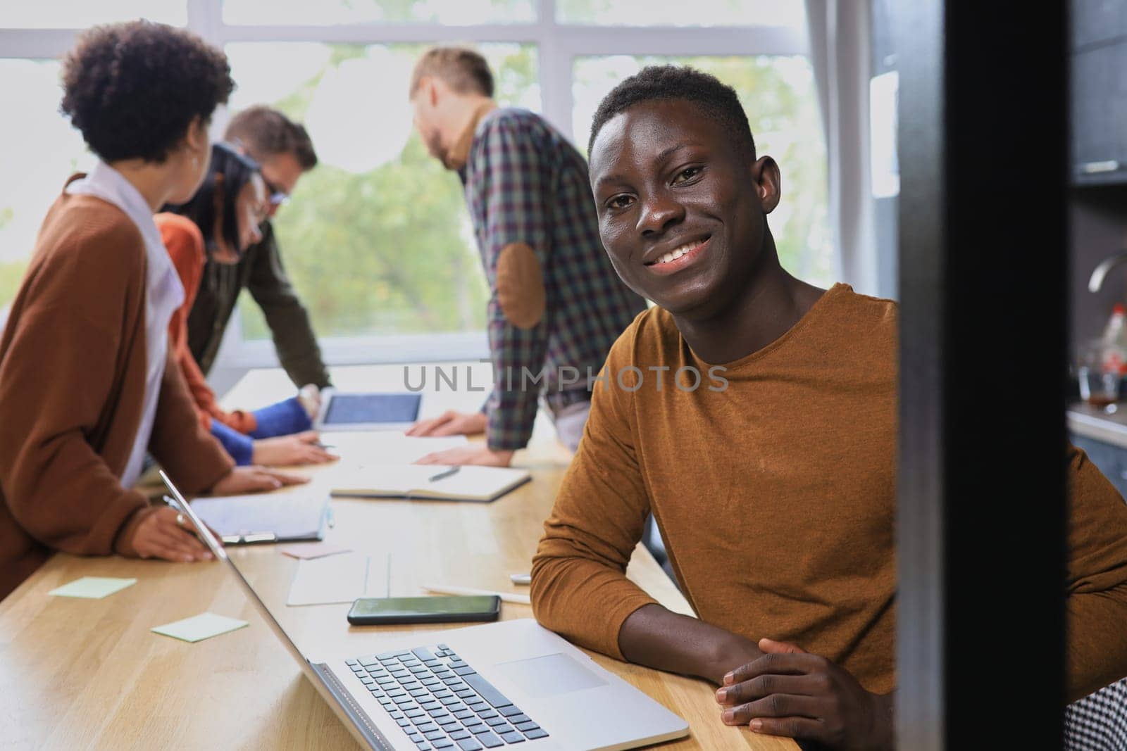 Portrait of a happy African American entrepreneur displaying computer laptop in office by asdf