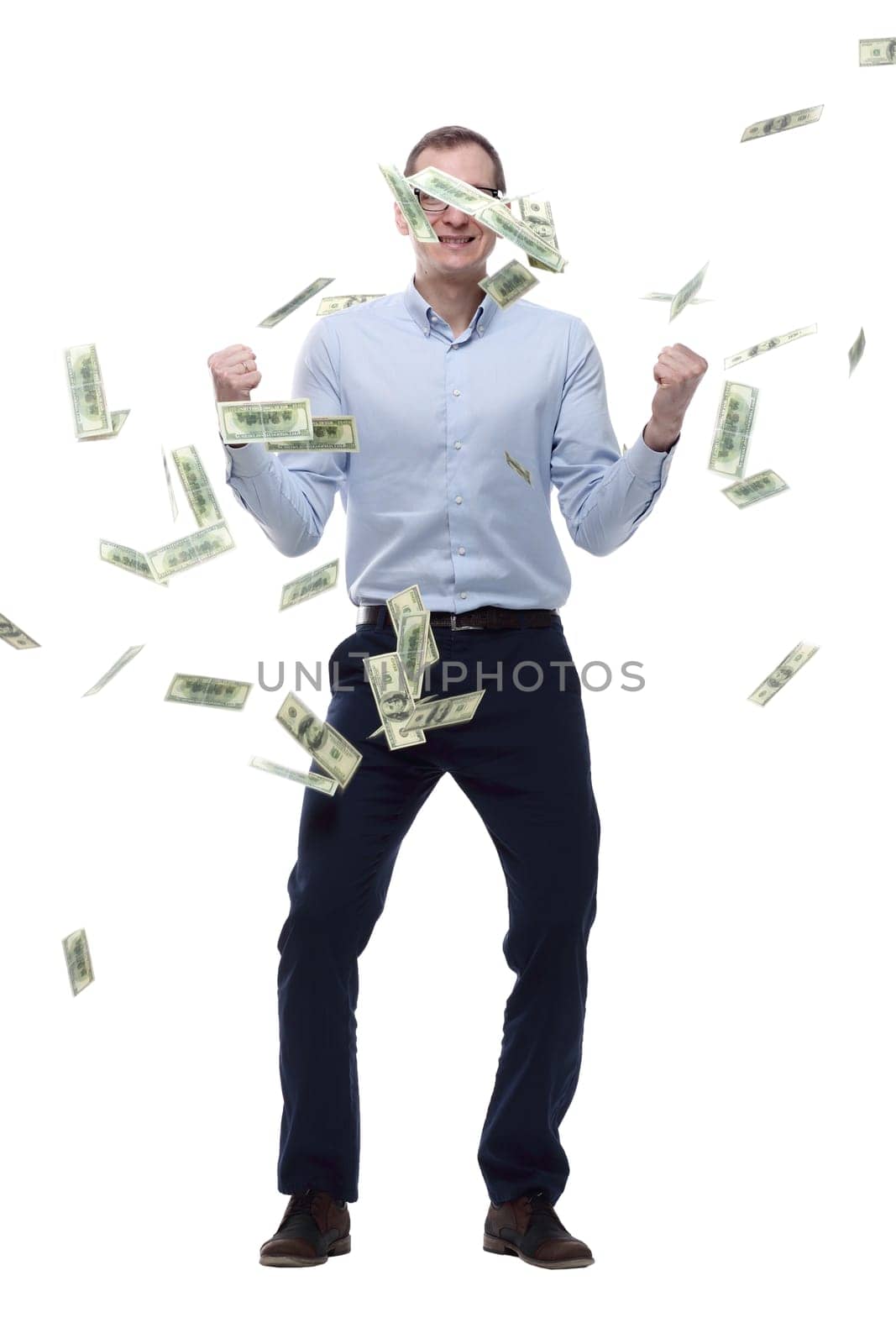 in full growth. happy man standing in the rain of banknotes. isolated on a white background