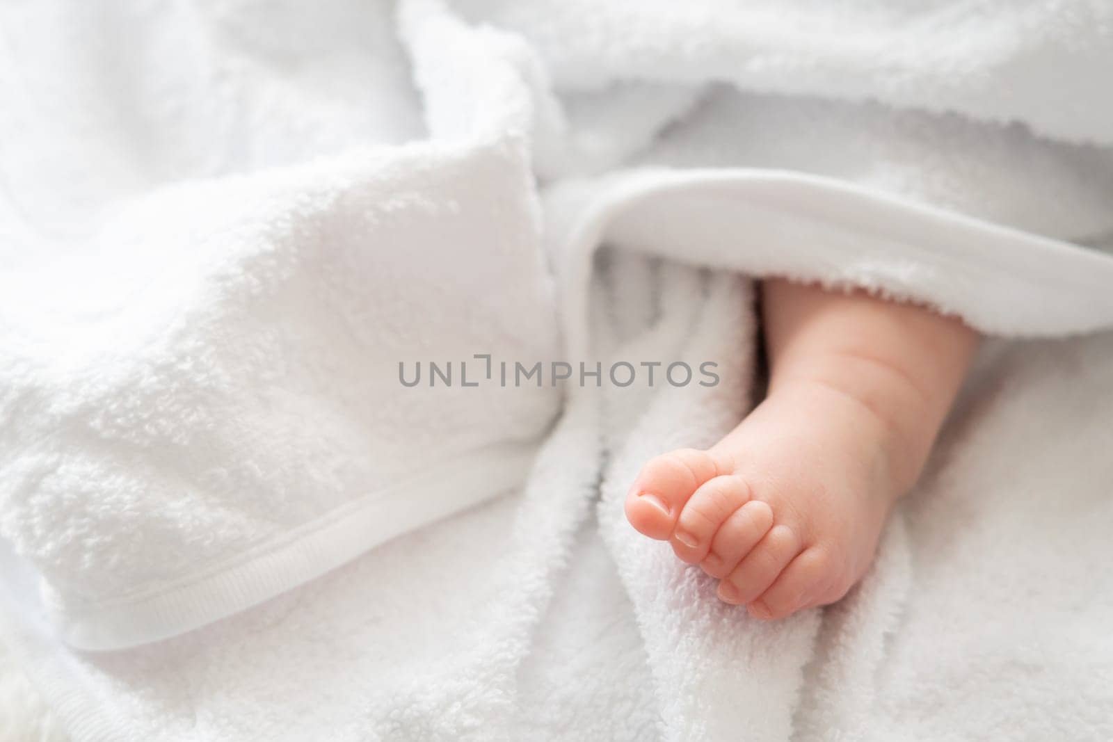 Infant's imprint: baby foot shyly emerging from white fabric by Mariakray