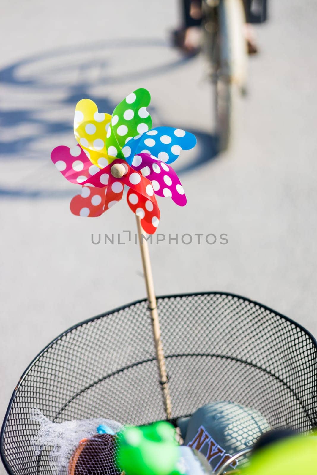 Colorful pinwheel attached to bicycle basket to entertain toddler child riding on front child seat on bike in summer. by kasto
