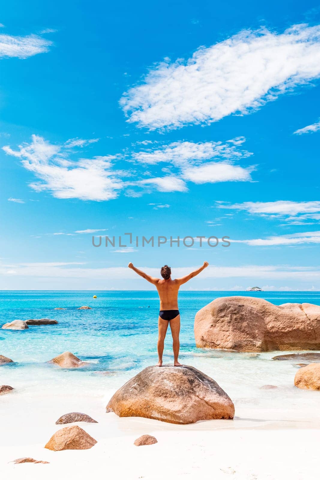 Happy man on the beautiful sandy beach rising hands to the sky on summer vacations on Seychelles. Freedom and happiness concept. by kasto