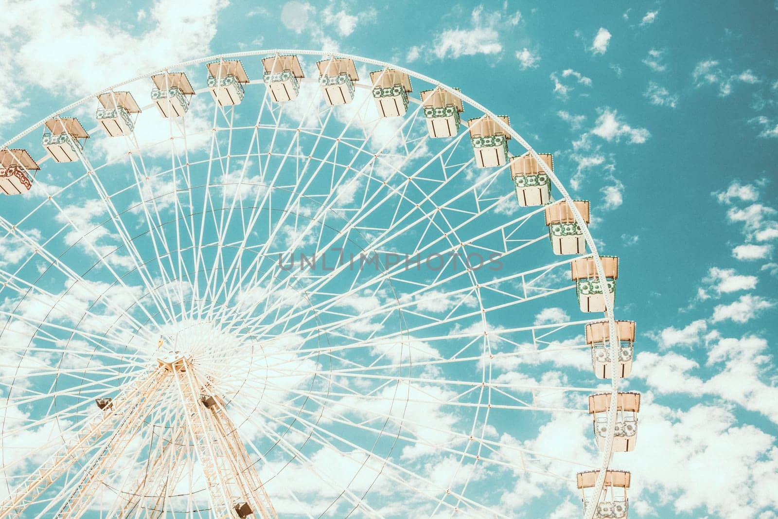 Ferris wheel of fair and amusement park. White clouds in the blue sky in background.