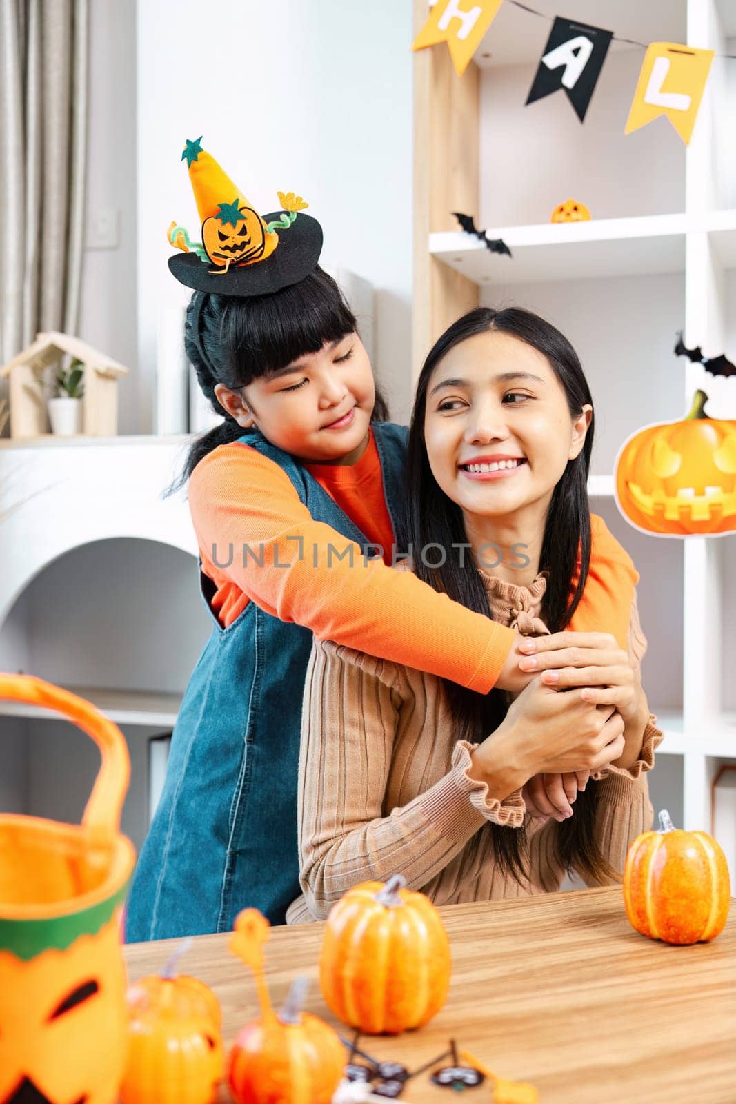 A joyful mother and daughter enjoying Halloween festivities with pumpkins and decorations in a cozy home setting.