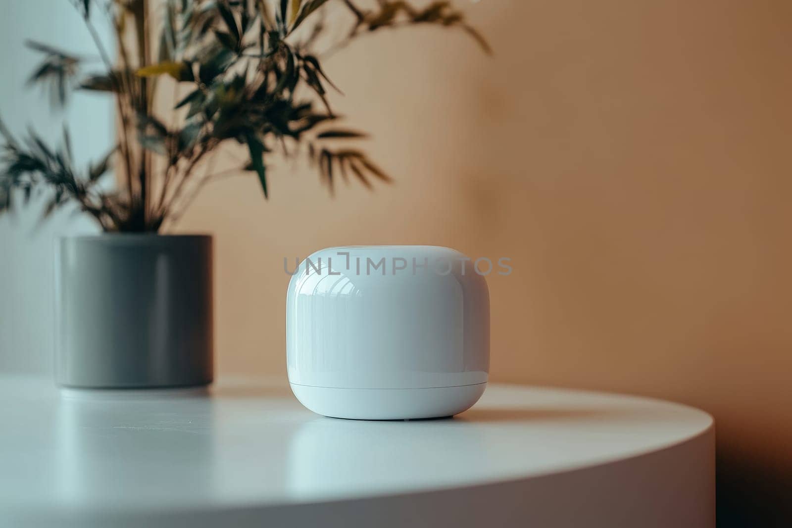 White smart home device on a table next to a potted plant, showcasing modern technology in a minimalist setting.