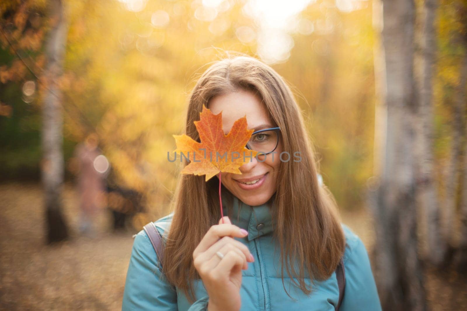 Autumn portrait of beautiful woman with maple leaves on fall nature background