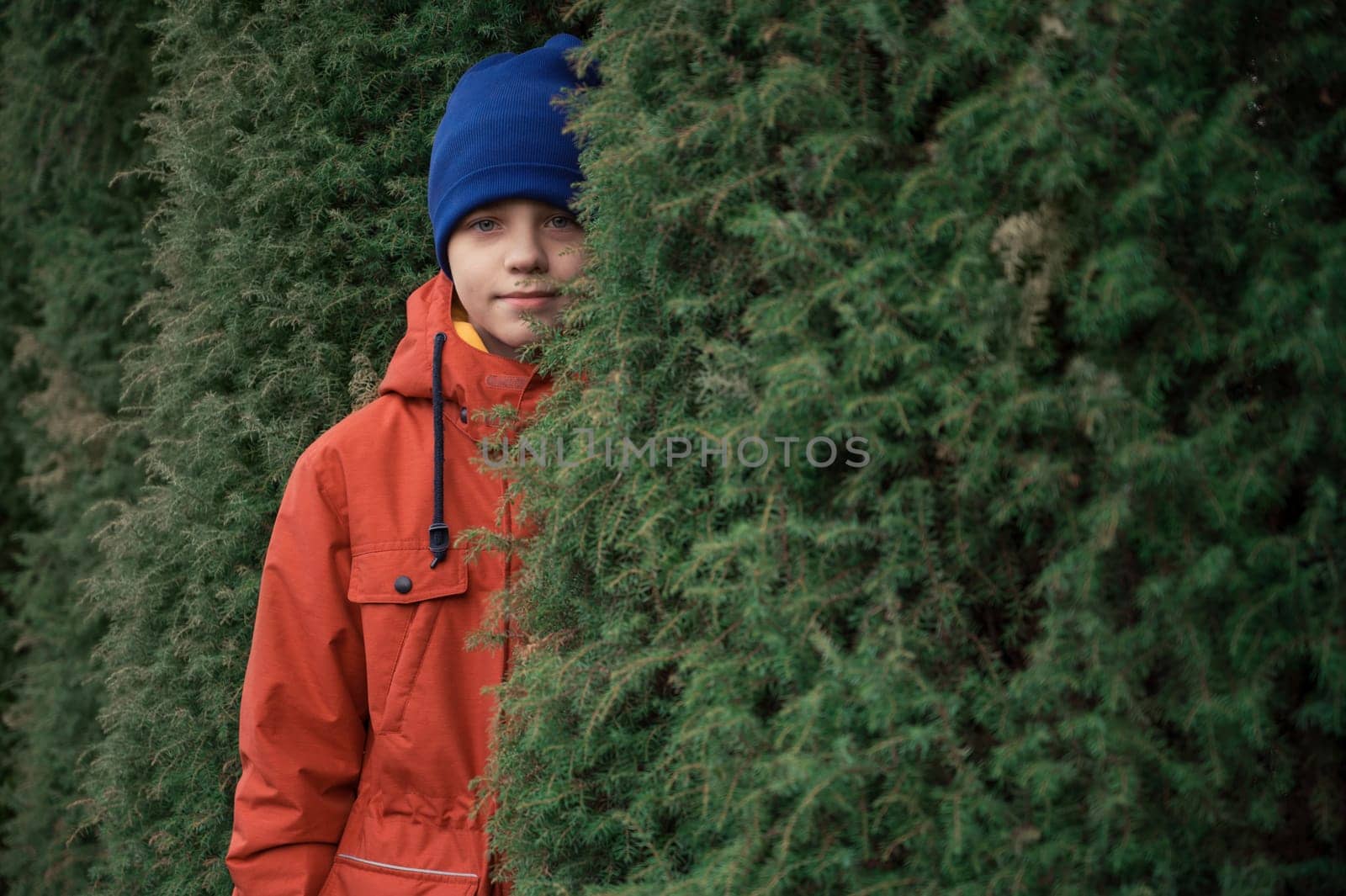 Autumn portrait of boy teen on thuja nature background