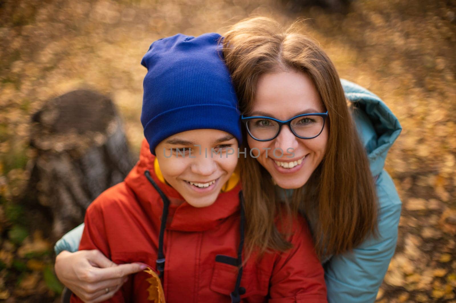 Autumn portrait of happy beautiful woman with her son on fall nature background