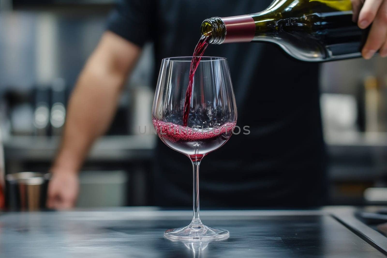 Close-up of red wine being poured into a glass by a sommelier in a restaurant setting.