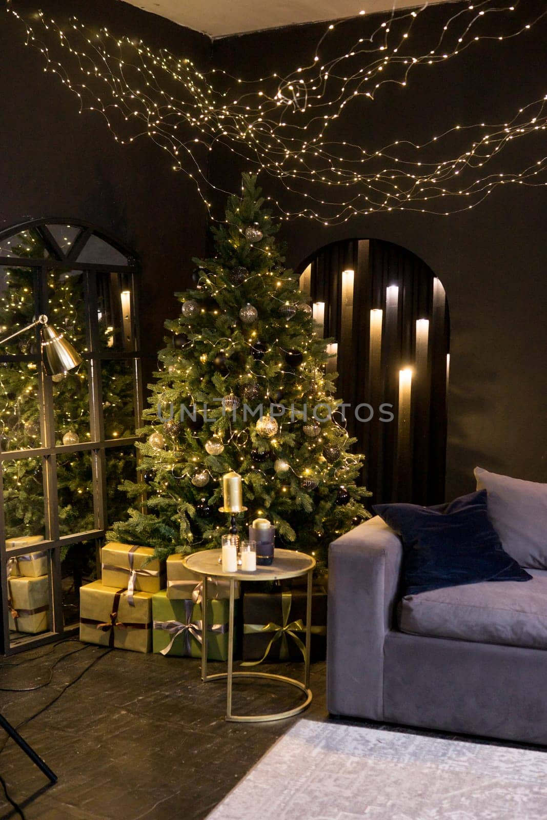 Christmas interior with a beautiful Christmas tree, sofa, light bulbs and dark background