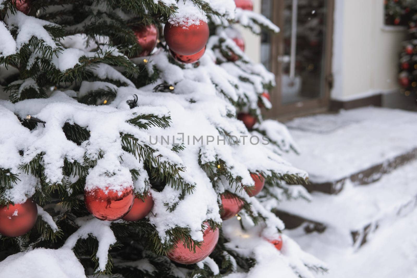 Christmas trees decorated with red balloons in front of the cafe entrance. Street New Year decorations.