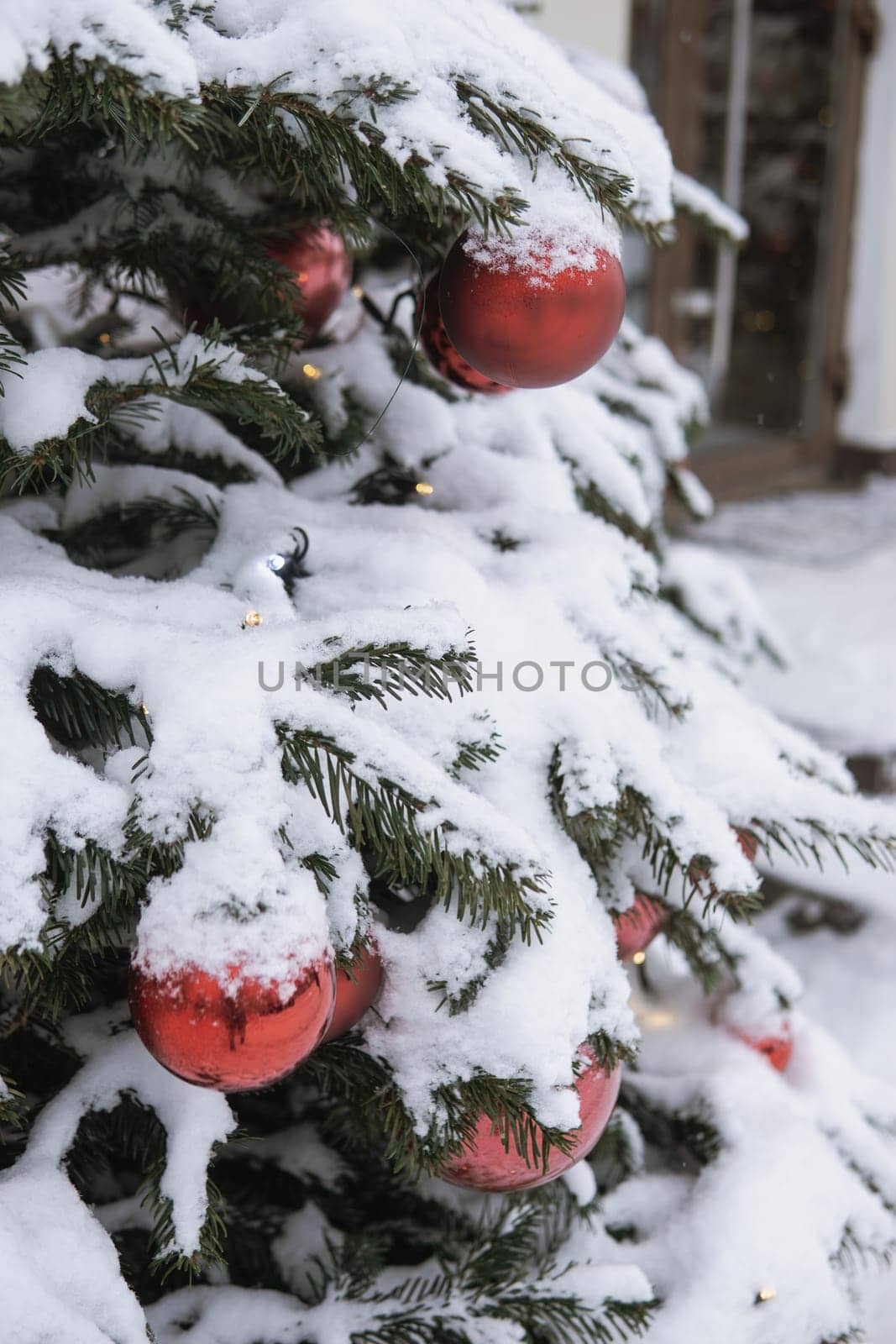 Christmas trees decorated with red balloons in front of the cafe entrance. Street New Year decorations.