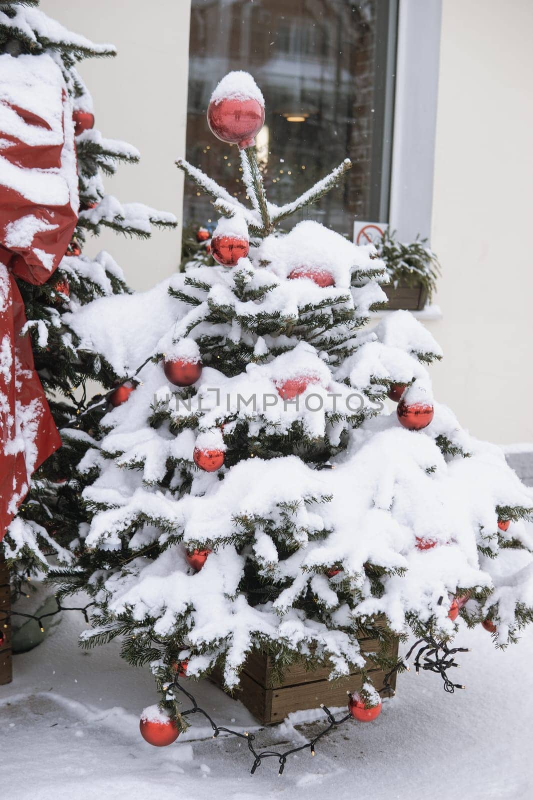 Christmas trees decorated with red balloons in front of the cafe entrance. Street New Year decorations.