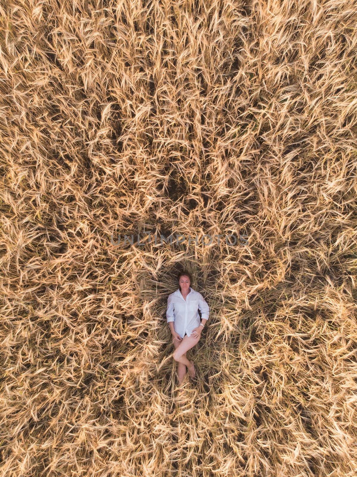 Aerial view of woman lying in the yellow field of wheat