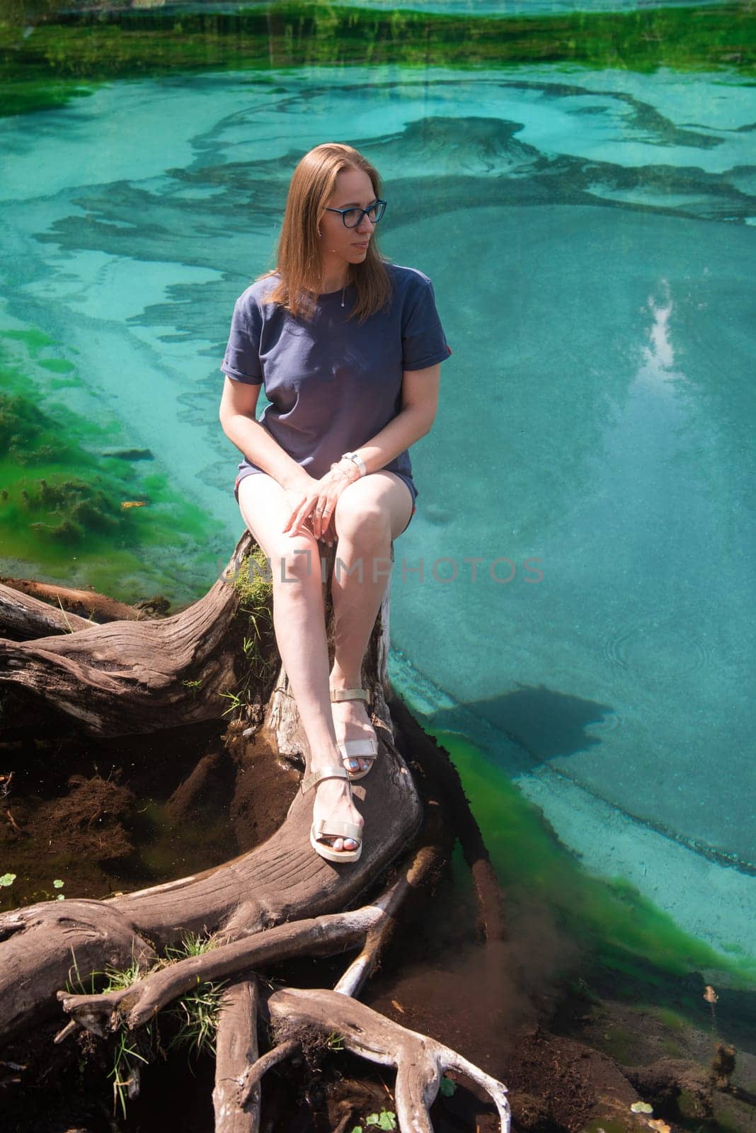 Woman at Beautiful Geyser lake with thermal springs that periodically throw blue clay and silt from the ground. Altai mountains, Russia