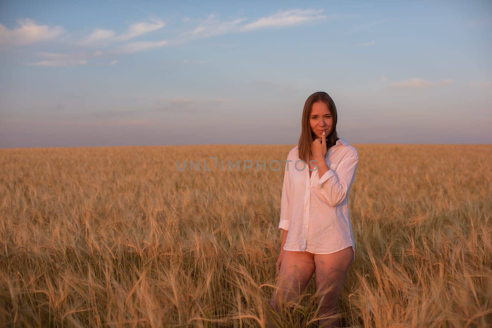Woman in the yellow field of wheat, beauty summer sunset