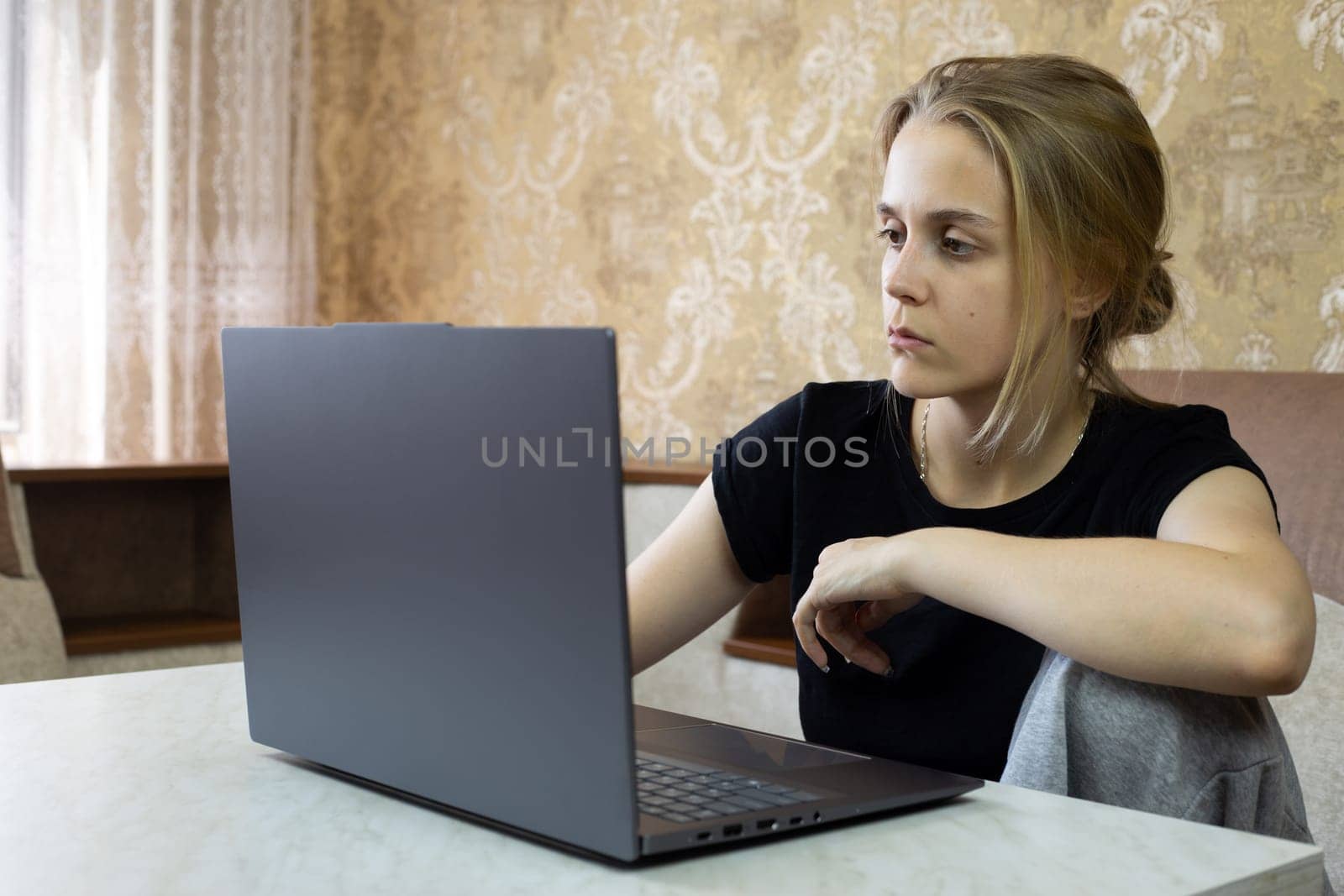 Tired girl works on laptop from home, online learning and work in modern world for people working at home in comfortable environment