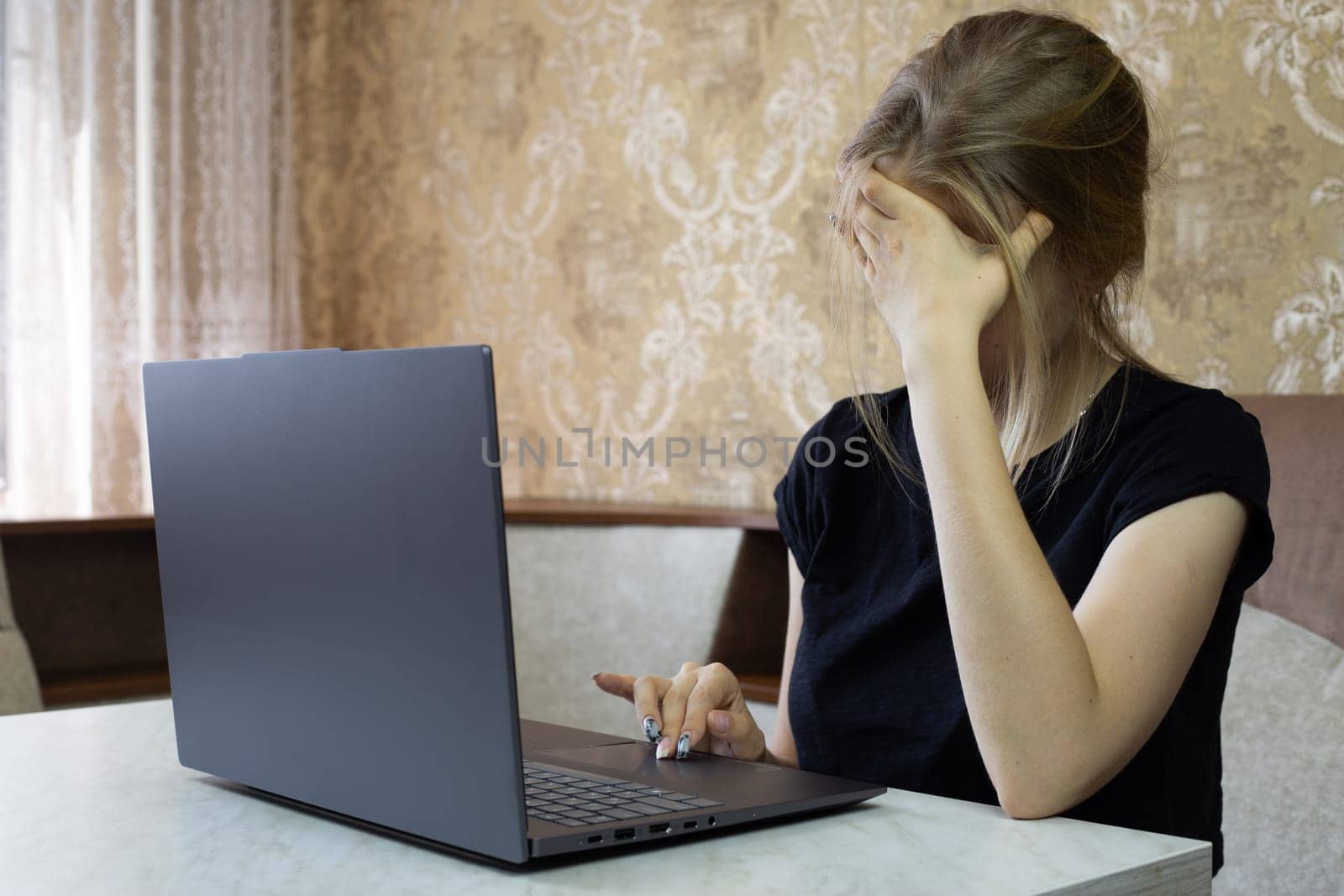 Girl is tired of working on laptop and falls asleep leaning on her arm, working on laptop from home, online learning and remote work causes lot of stress for girl worker