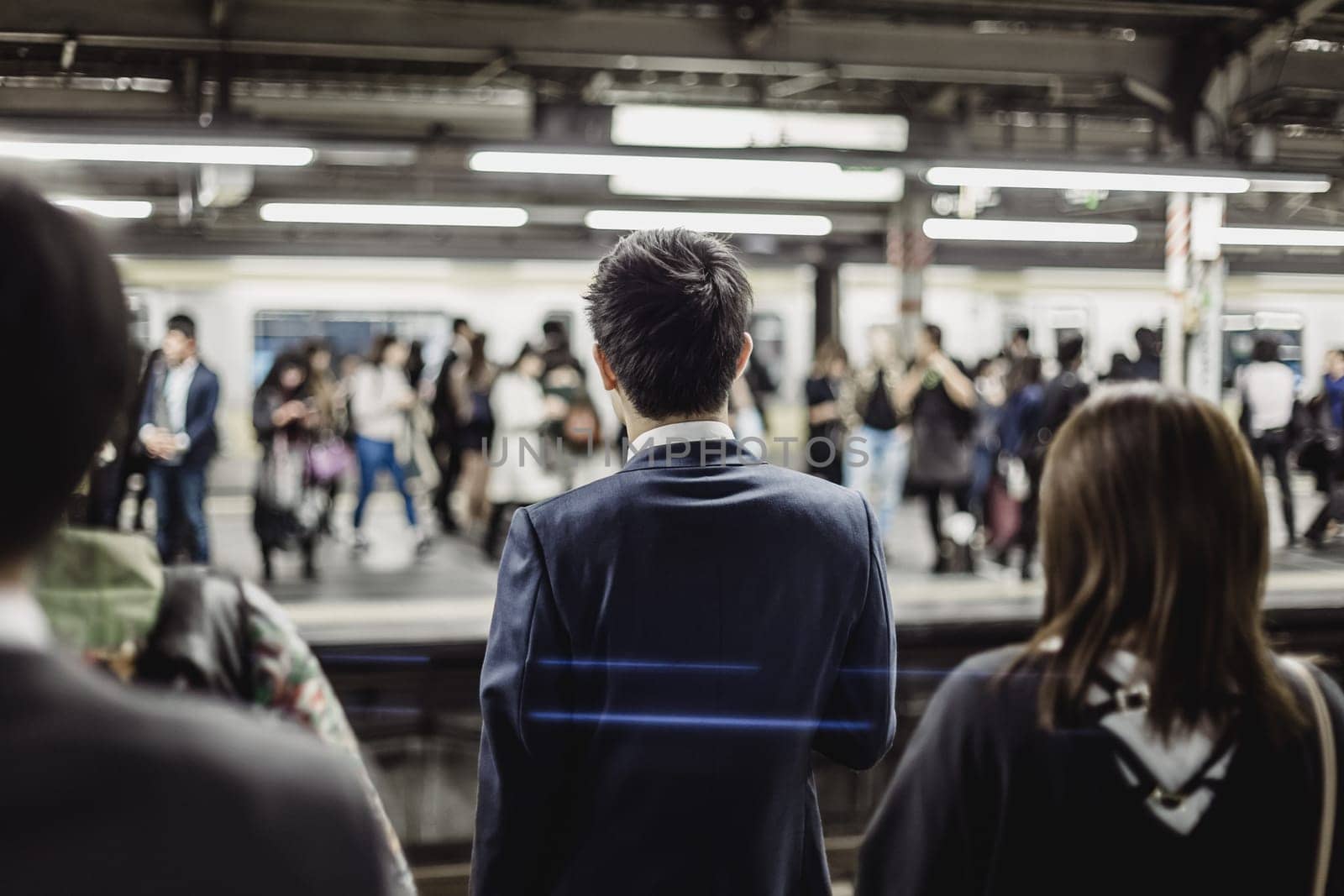 Passengers traveling by Tokyo metro. Business people commuting to work by public transport in rush hour. Shallow depth of field photo.