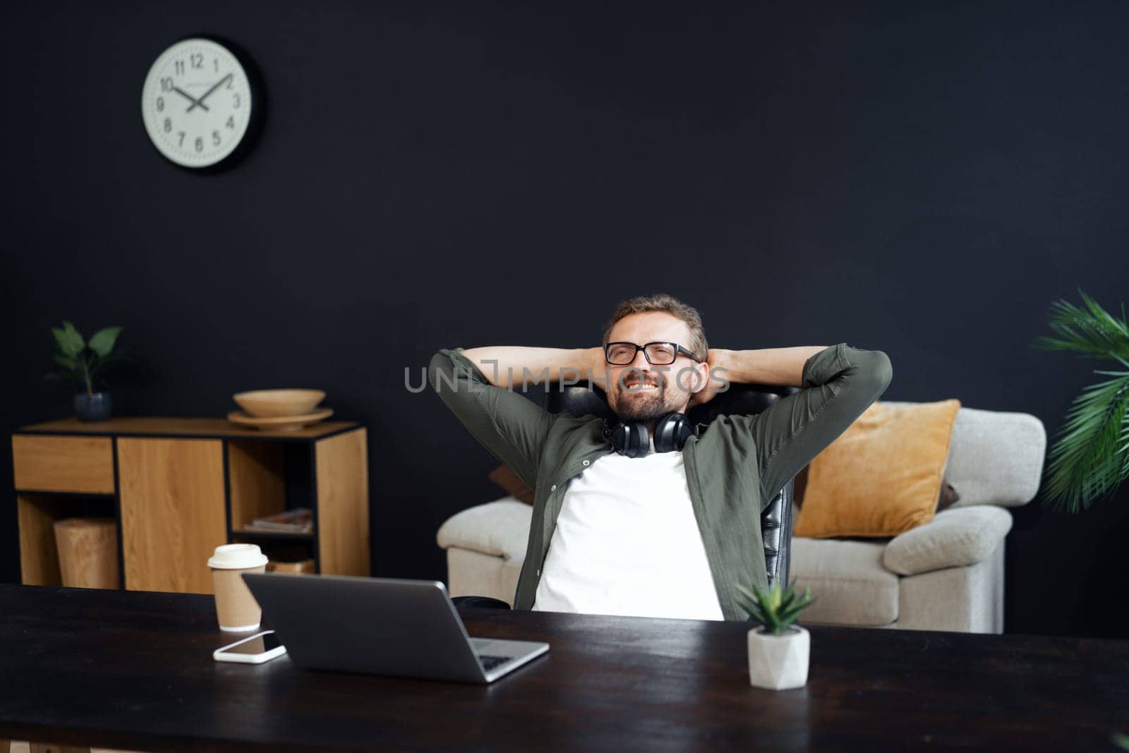 Weary man takes well-deserved break in office chair, reclining and unwinding after long workday. Finding solace and relief in corporate world, where moments of rest become cherished necessity for rejuvenation. High quality photo