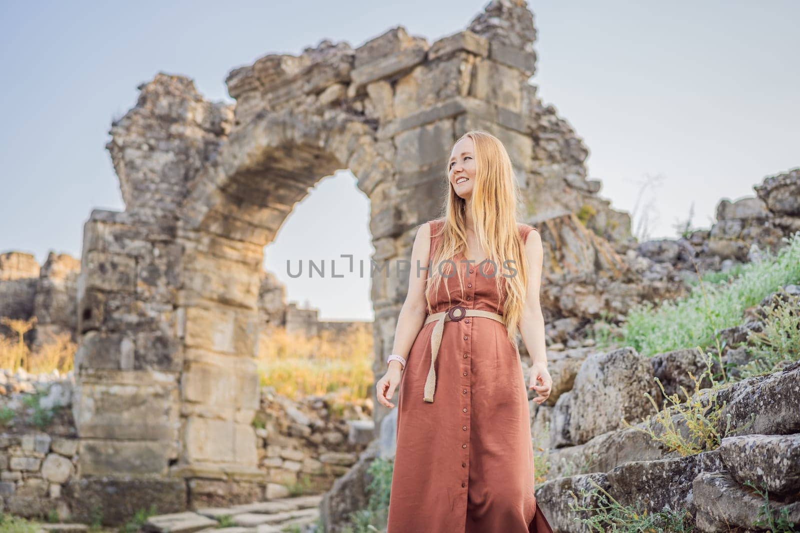 Woman tourist explores Aspendos Ancient City. Aspendos acropolis city ruins, cisterns, aqueducts and old temple. Aspendos Antalya Turkey. turkiye.