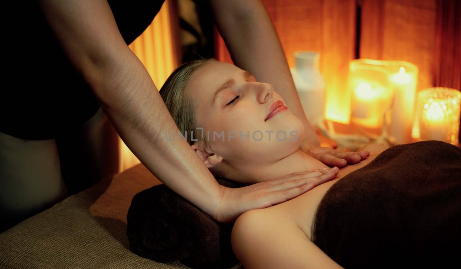 Caucasian woman customer enjoying relaxing anti-stress spa massage and pampering with beauty skin recreation leisure in warm candle lighting ambient salon spa at luxury resort or hotel. Quiescent