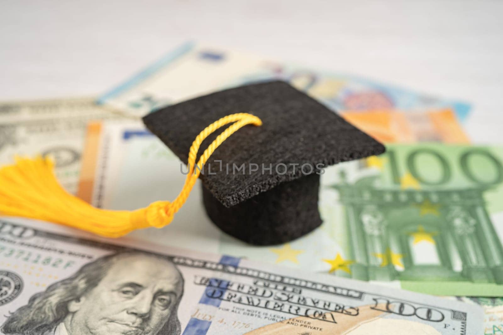 Graduation gap hat on Euro and US dollar banknotes money, Education study fee learning teach concept. by pamai