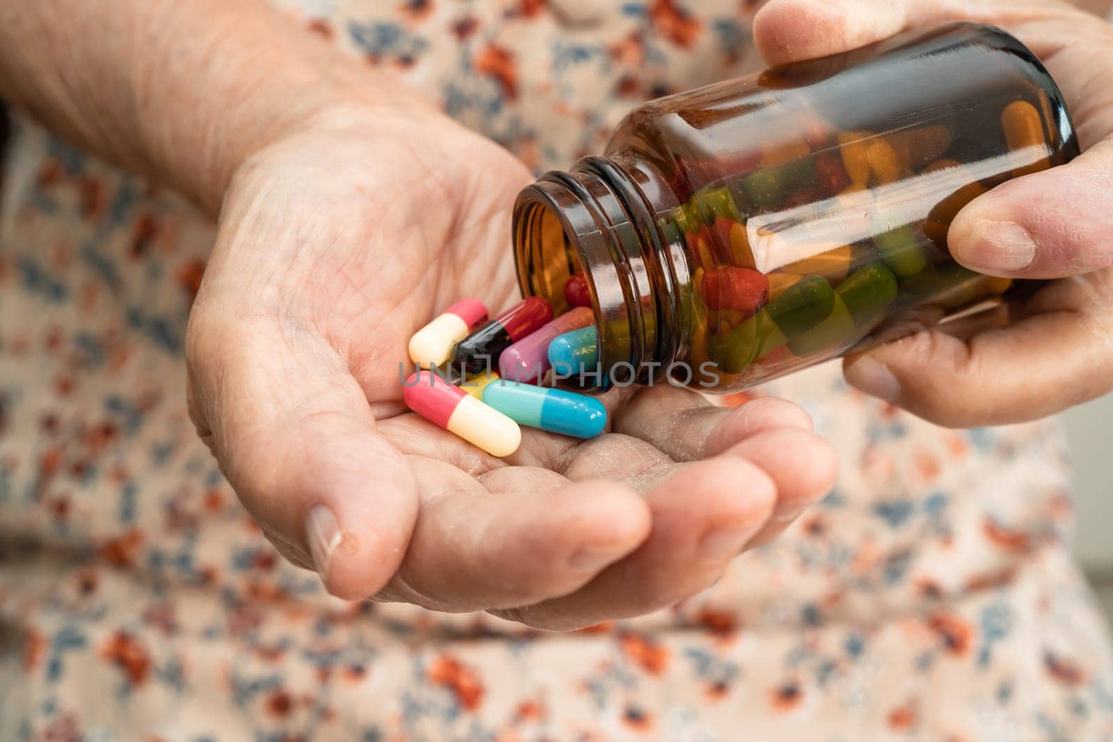 Asian senior woman patient holding antibiotics capsule pills  for treatment infection patient in hospital, Pharmacy drugstore concept.