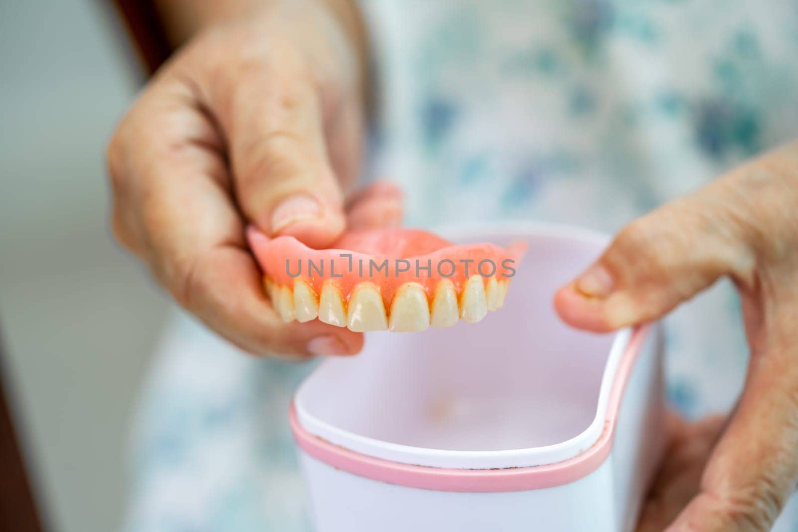 Asian elderly woman patient holding to use denture, healthy strong medical concept. by pamai