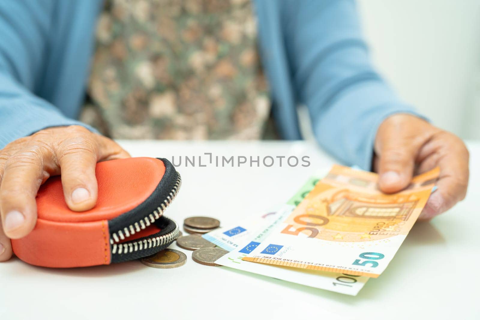 Asian senior woman holding counting coin money and Euro bnaknotes in purse. Poverty, saving problem in retirement.