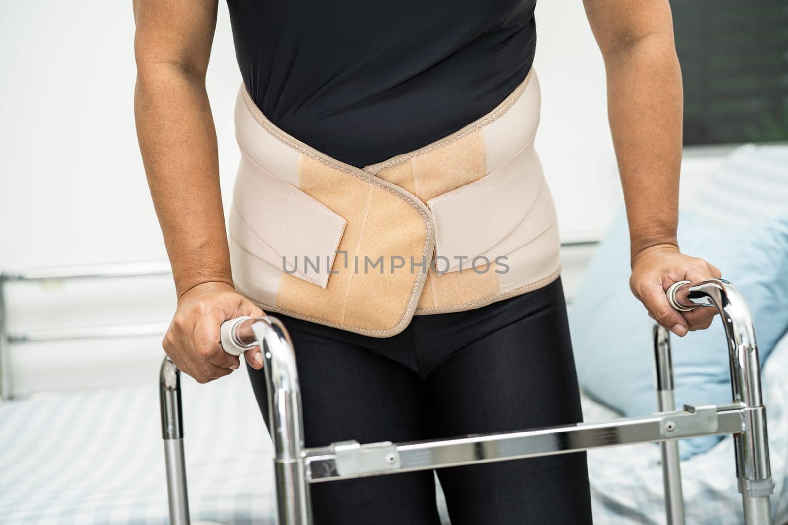 Asian lady patient wearing back pain support belt for orthopedic lumbar with walker.