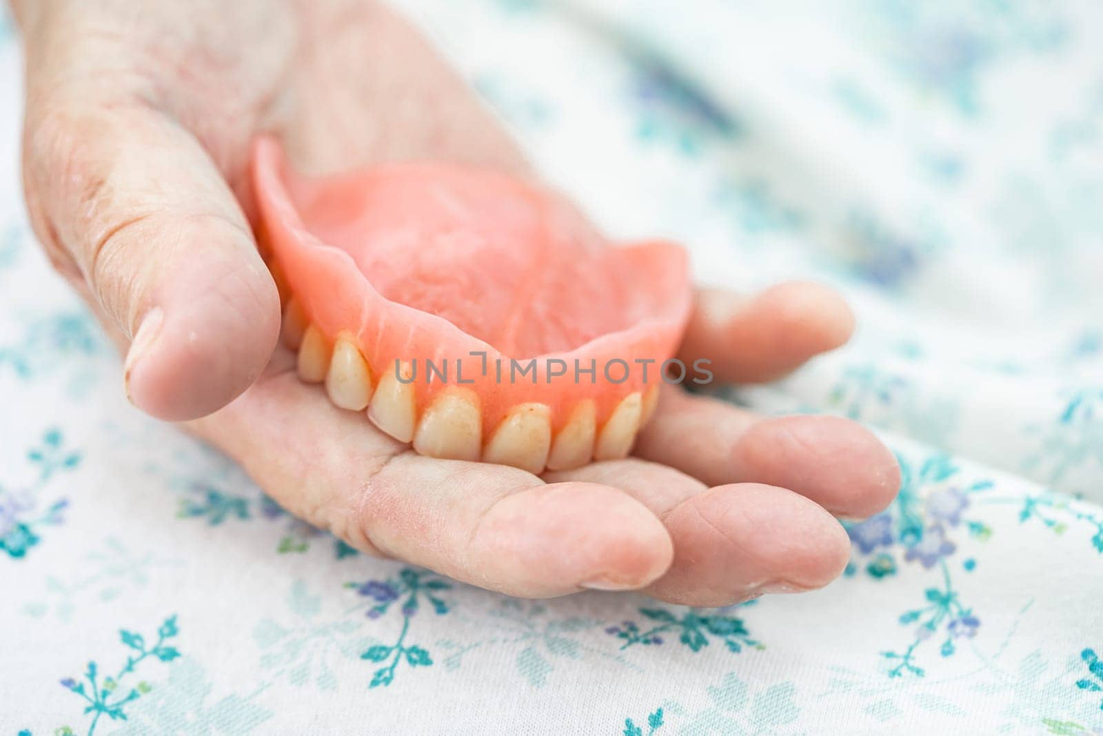 Asian elderly woman patient holding to use denture, healthy strong medical concept. by pamai