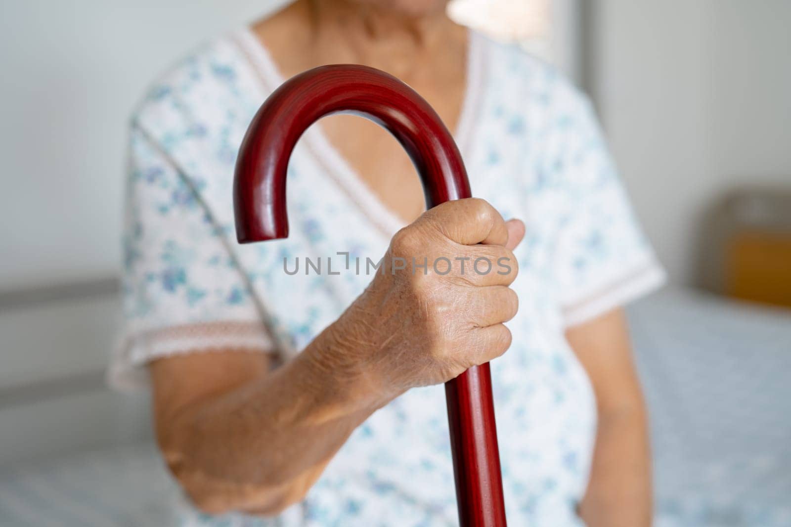 Asian elderly disability woman holding waling stick, wood cane, round handle, walking aid for help to walk.