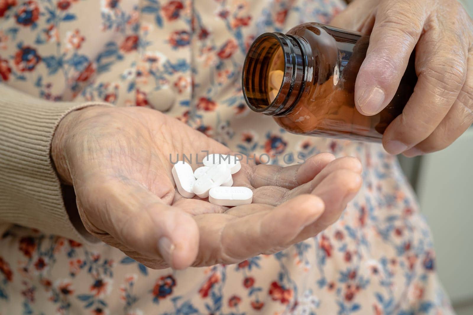 Asian senior woman patient holding antibiotics capsule pills  for treatment infection patient in hospital, Pharmacy drugstore concept.