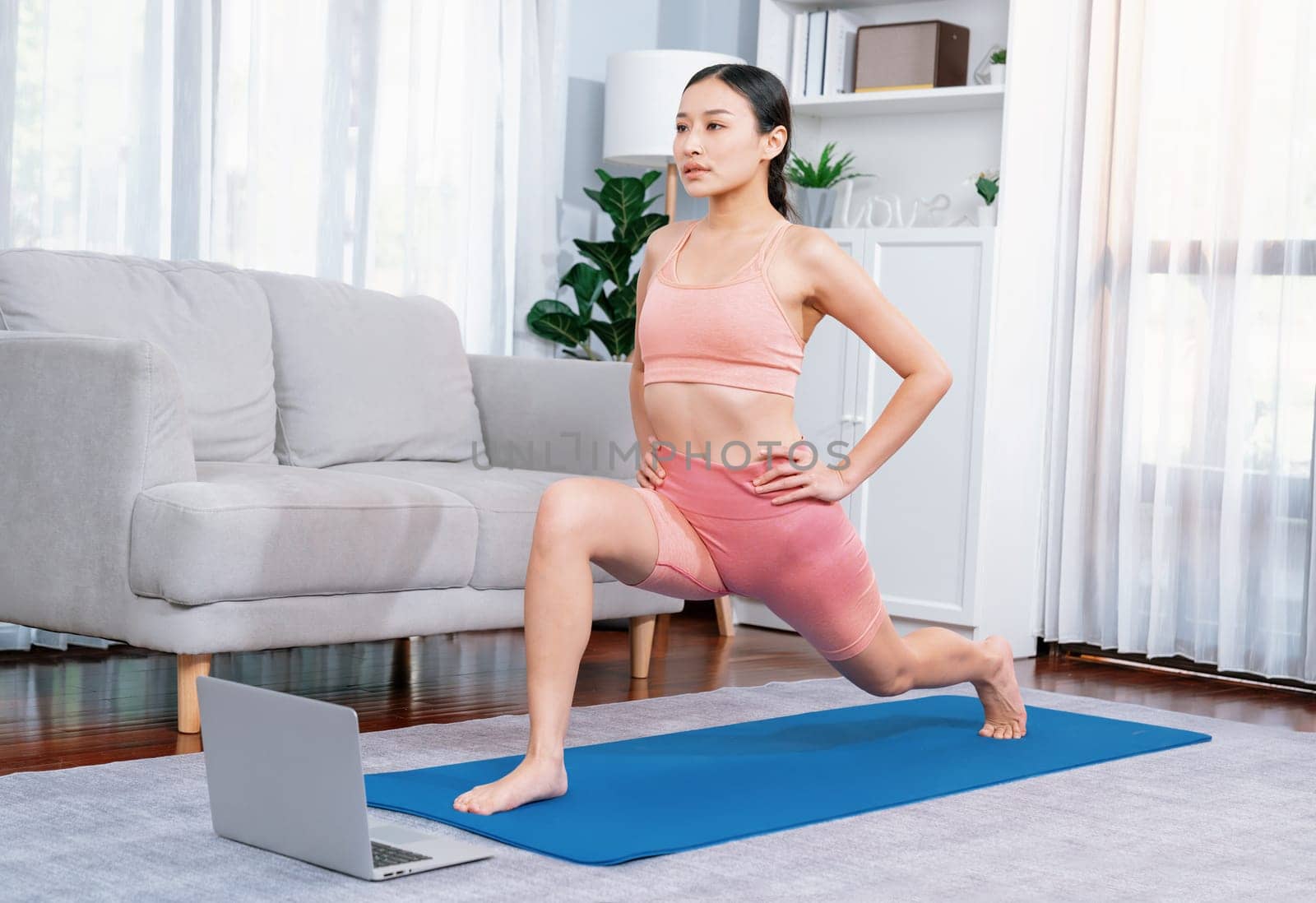 Asian woman in sportswear and yoga exercise on fitness mat with laptop. Vigorous by biancoblue
