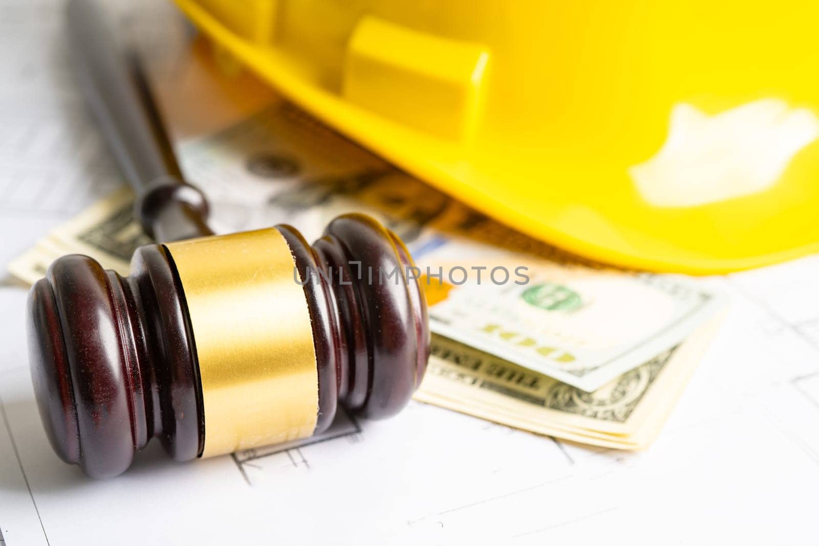 Architectural house plan project blueprint and Judge gavel hammer with yellow helmet and US dollar banknotes, Engineer and construction law and justice.  by pamai