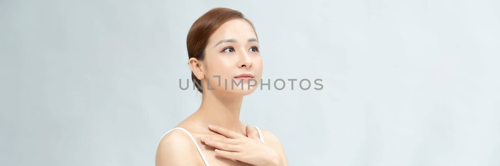 Youthful pretty Asian woman with hand touching face on white background for web banner by makidotvn