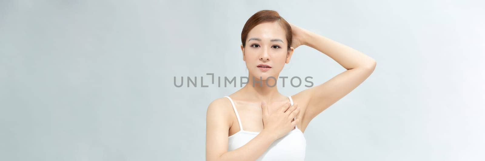 Young Asian woman lifting hands up to show off clean and hygienic armpits or underarms. Banner by makidotvn
