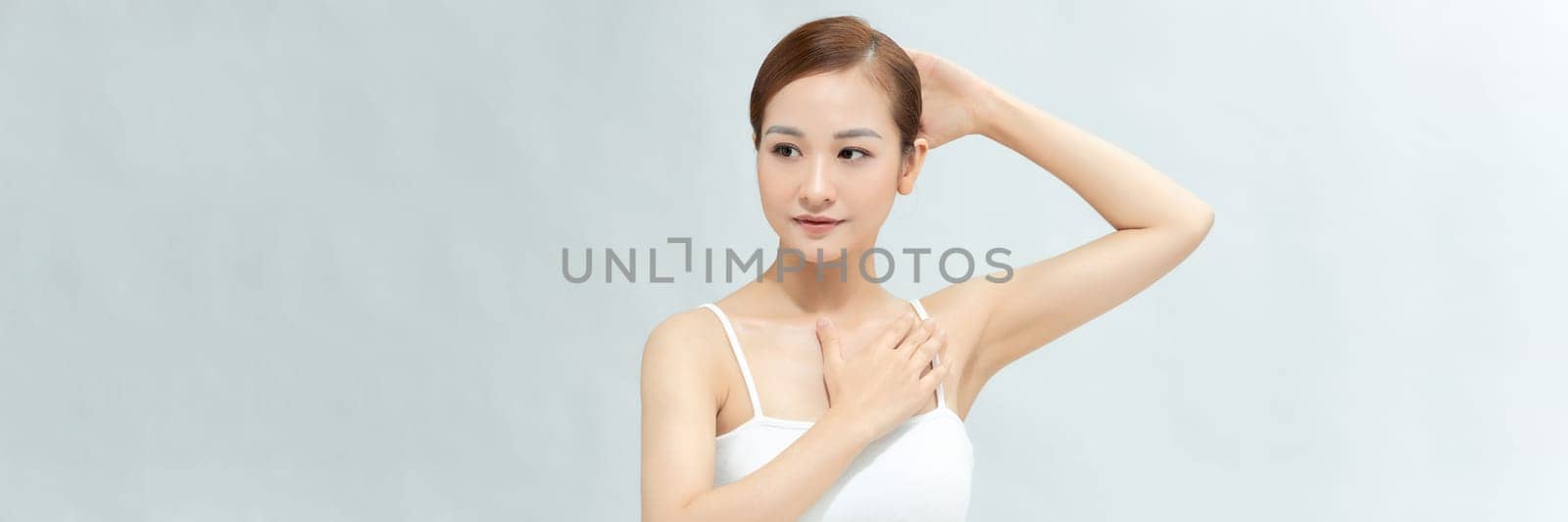 Young Asian woman lifting hands up to show off clean and hygienic armpits or underarms. Banner