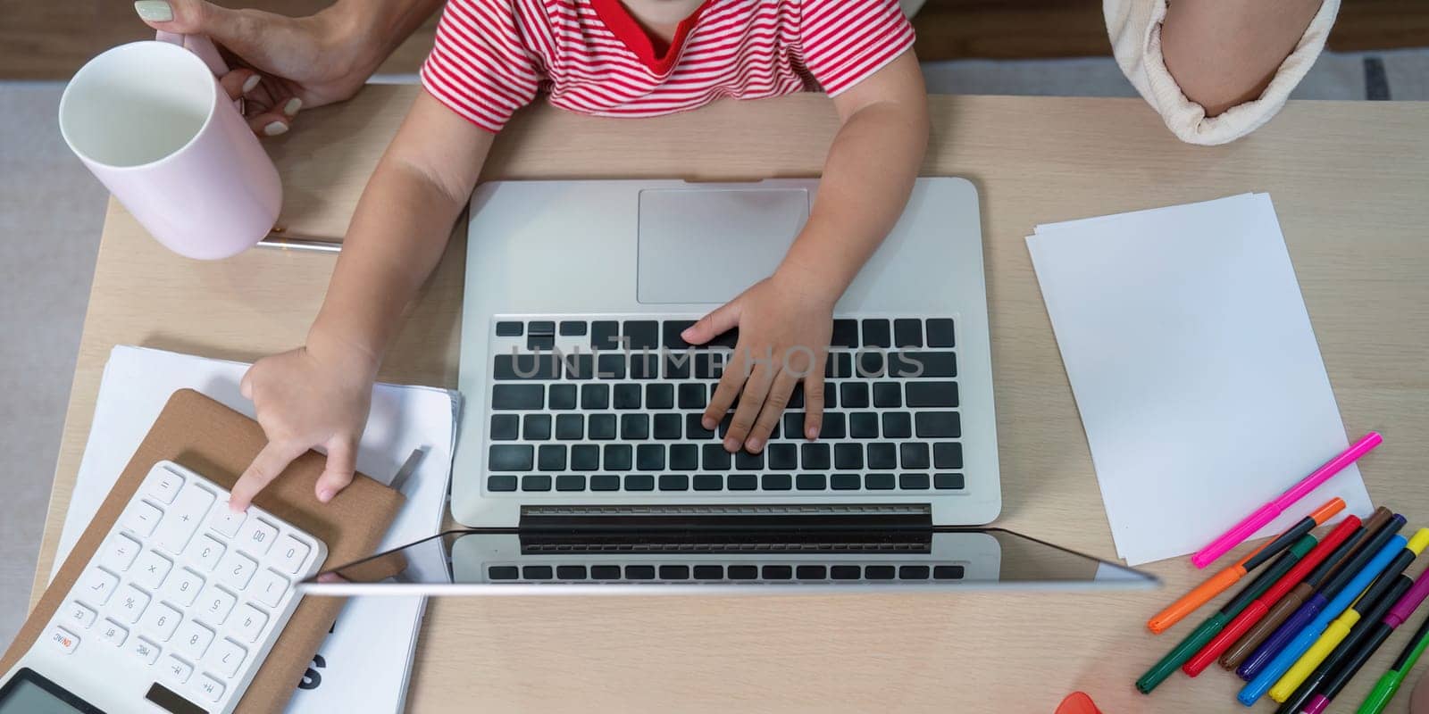 A mother and daughter working together at home, using a laptop and calculator, showcasing modern family lifestyle and multitasking.