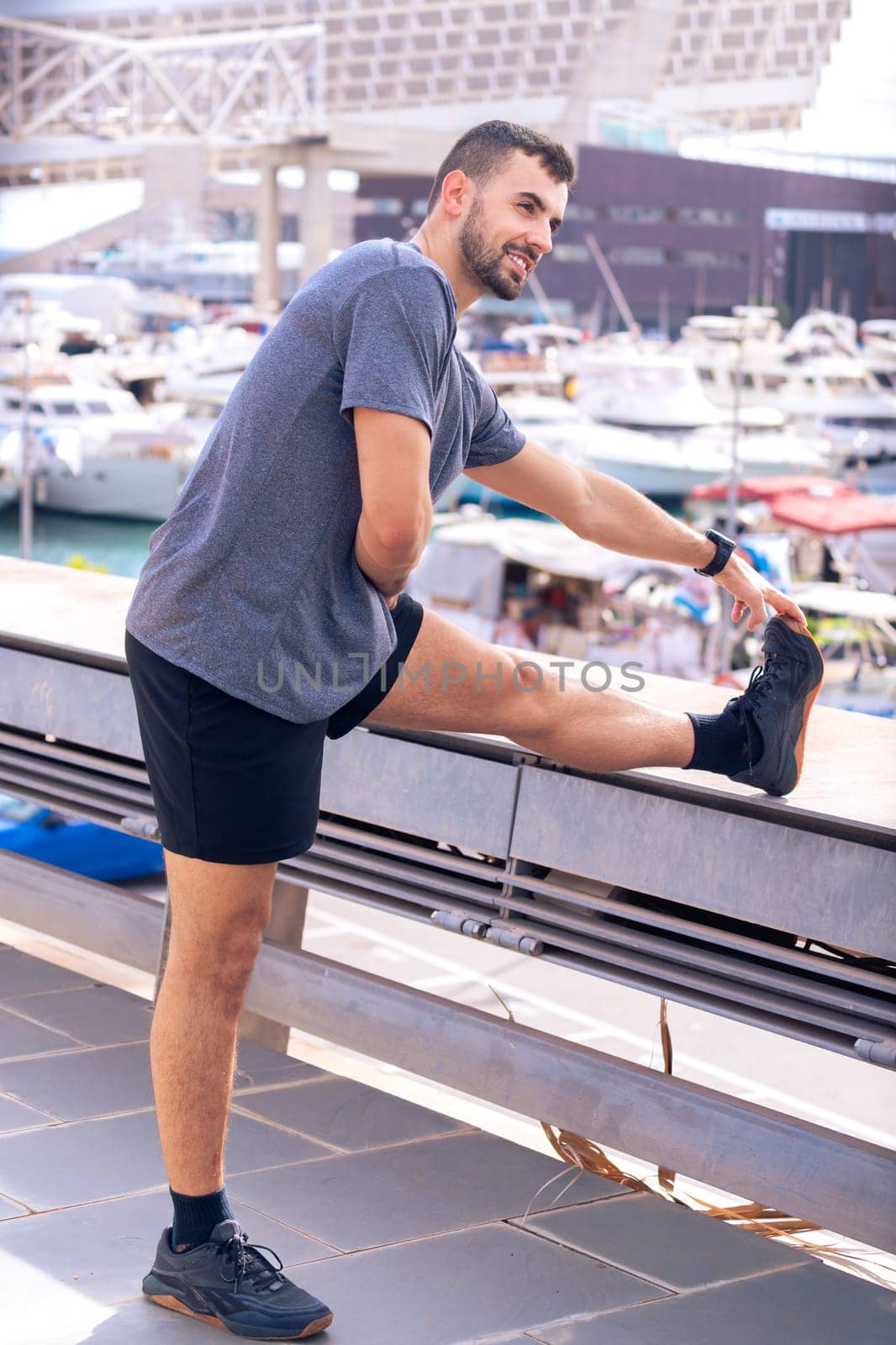 Young sportsman with concentrated sports watch stretching before training outdoors.Vertical