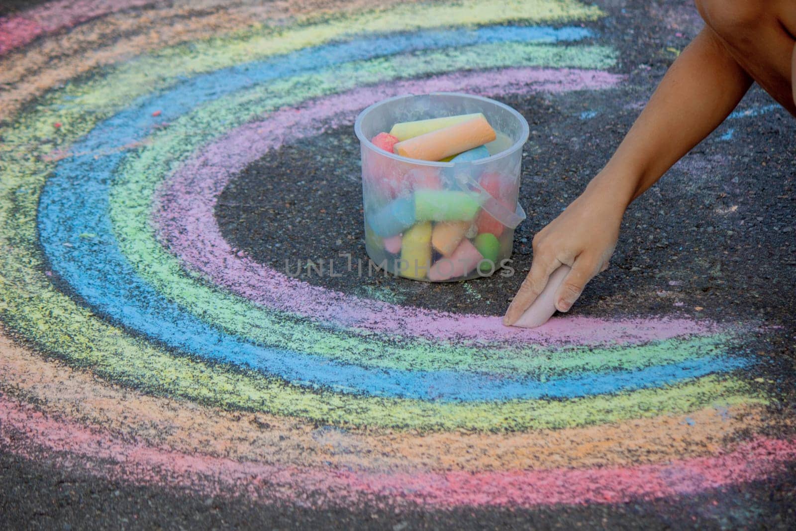 the boy draws with chalk on the asphalt. Selective focus.